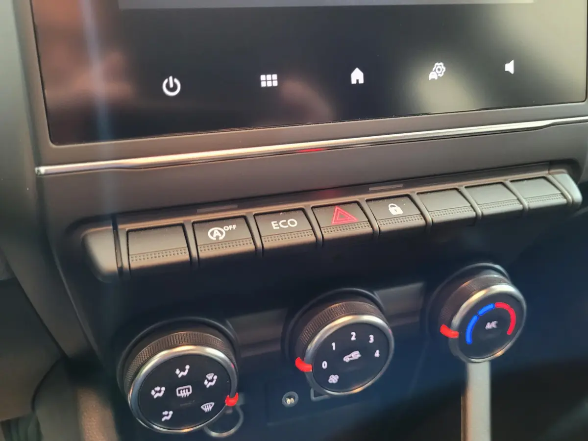Gros plan sur la console centrale de la Renault Clio gris foncé, montrant les commandes climatisation et boutons fonctionnels.