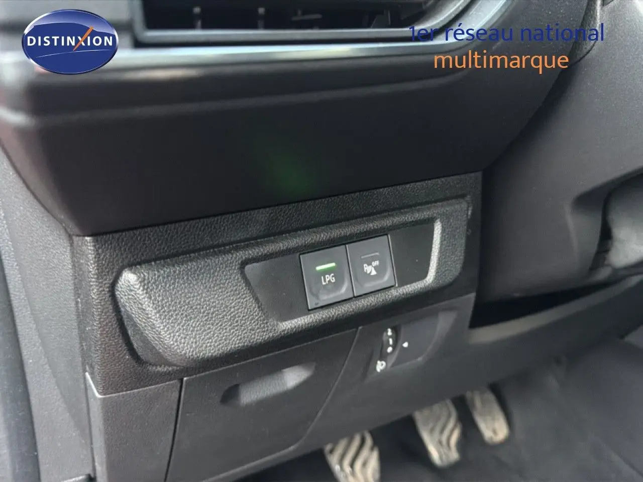 Gros plan sur les commandes LPG et assistance stationnement du tableau de bord d'une Dacia Sandero Stepway rouge fusion 2021.