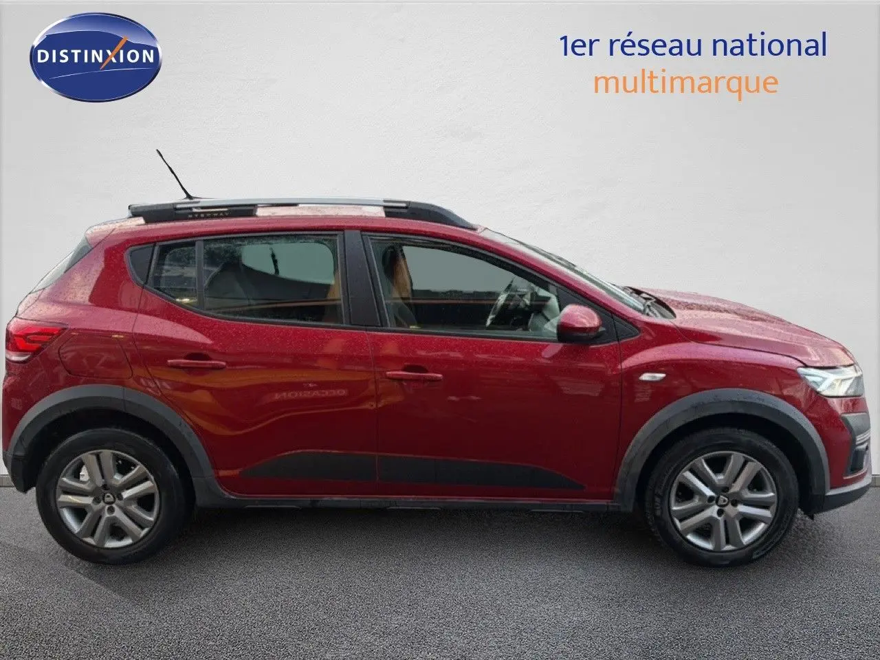 Profil droit d'une Dacia Sandero Stepway rouge fusion de 2021 avec barres de toit et jantes alliage.