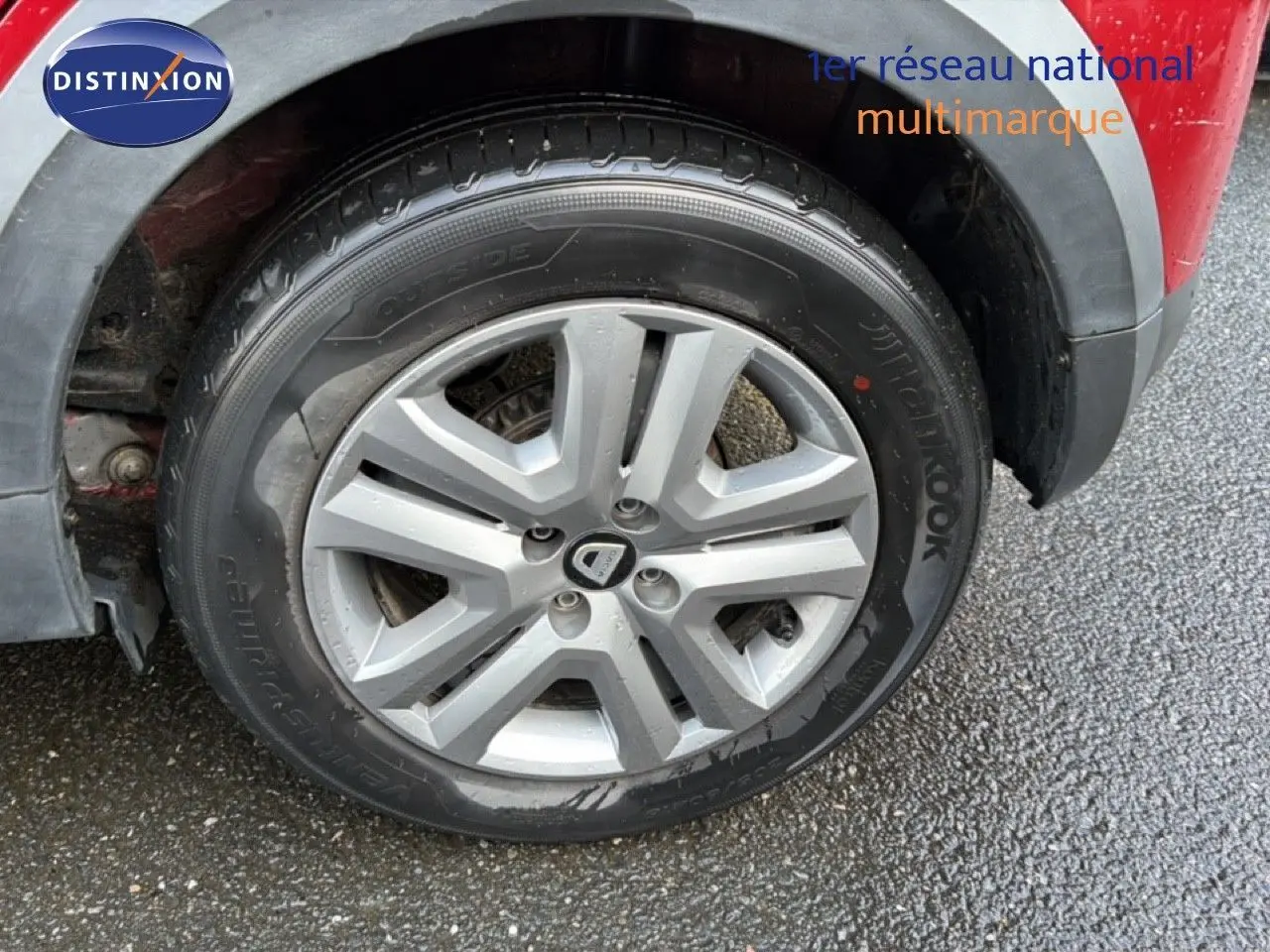 Gros plan sur la roue avant droite d'une Dacia Sandero Stepway rouge fusion, mettant en valeur la jante en alliage gris.