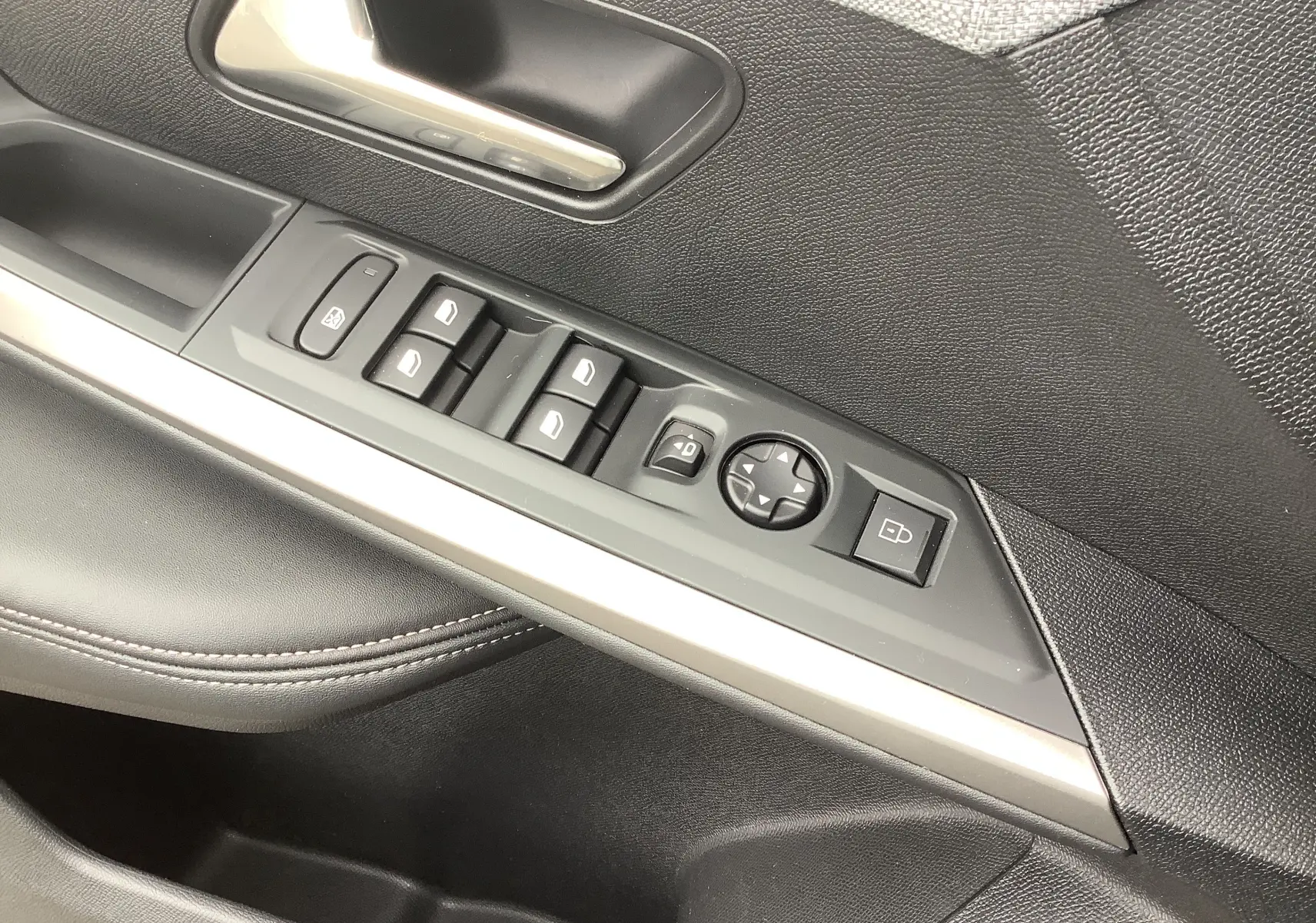 Gros plan sur la commande des vitres et rétroviseurs côté gauche intérieur noir du Peugeot 3008 Hybrid 2024.