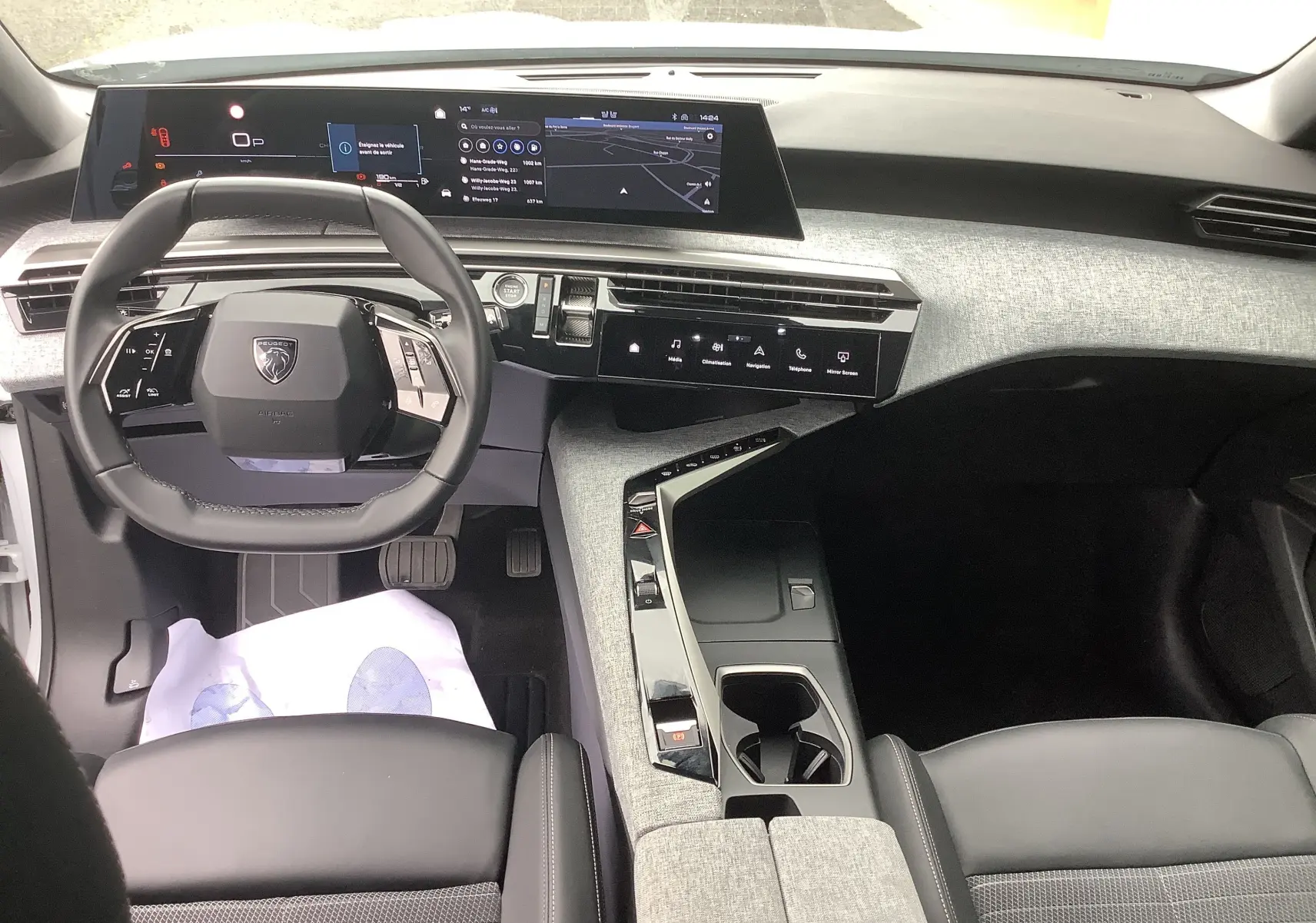 Vue intérieure avant du Peugeot 3008 Hybrid 2024, tableau de bord numérique et volant compact en cuir noir.