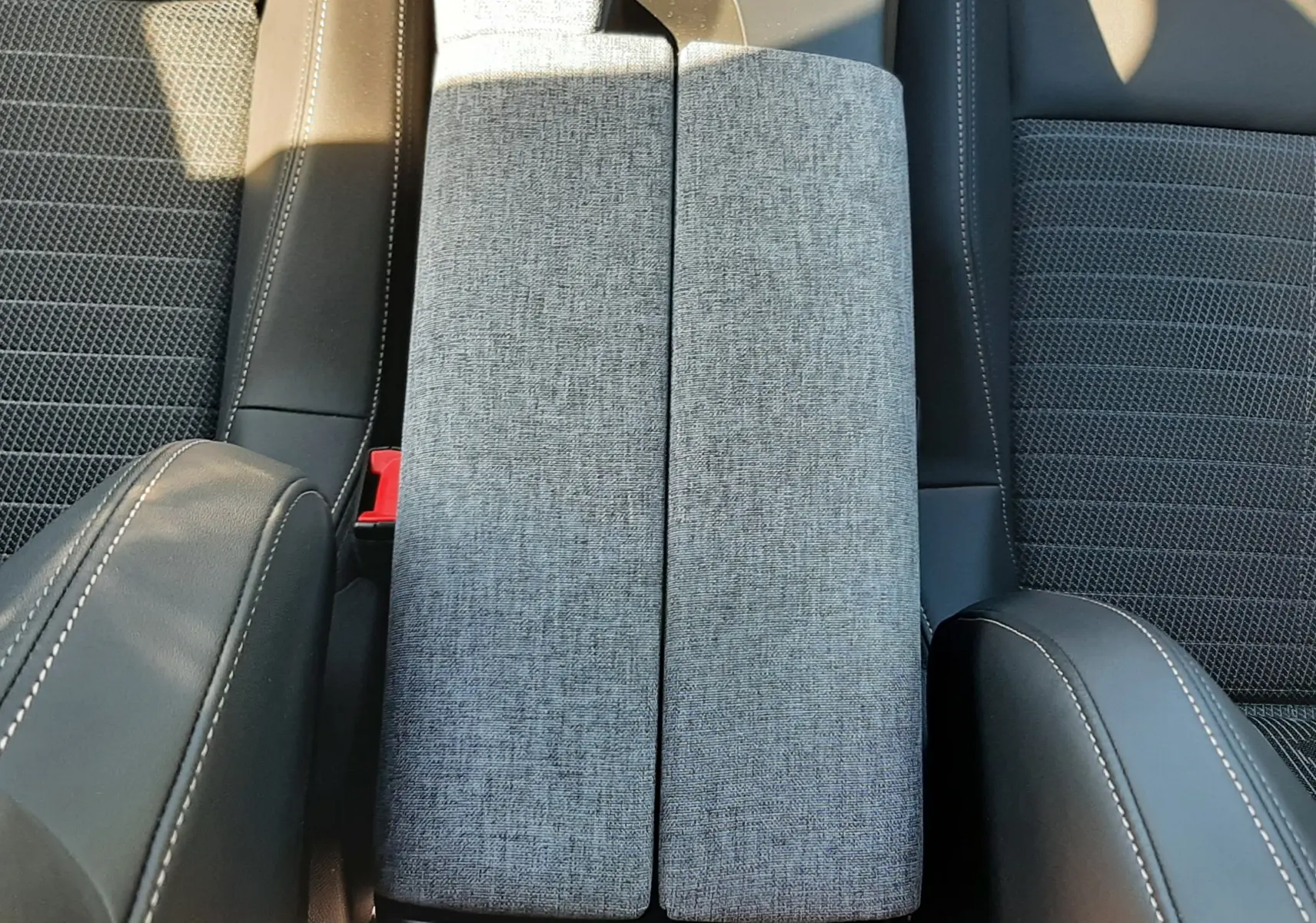 Vue plongeante sur la console centrale tissu gris et sièges noirs en tissu et cuir du Peugeot 3008 Hybrid 2024.