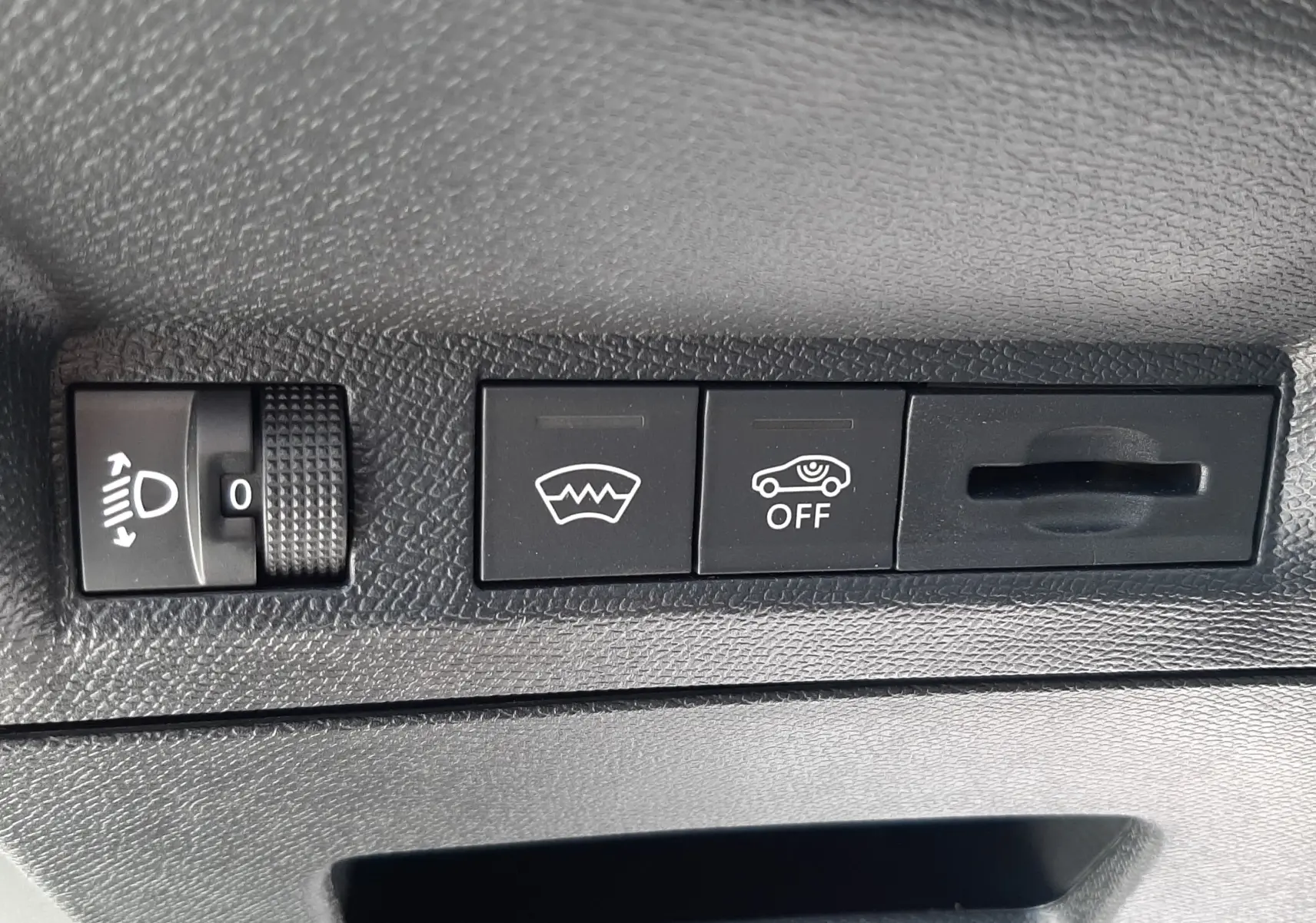 Détail des commandes intérieures noires avec réglage des phares et boutons de désembuage et assistance sur Peugeot 3008 blanc.