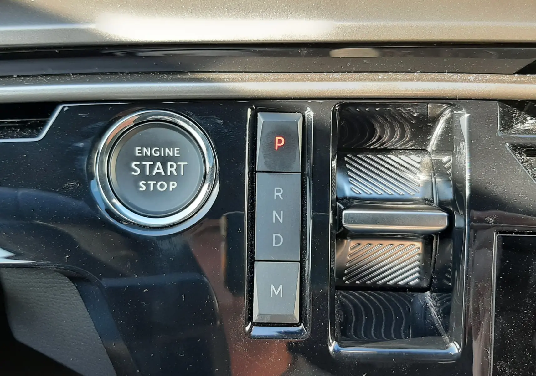Gros plan sur la console centrale noire brillante du Peugeot 3008 blanc, montrant le bouton start/stop et la commande de boîte automatique.