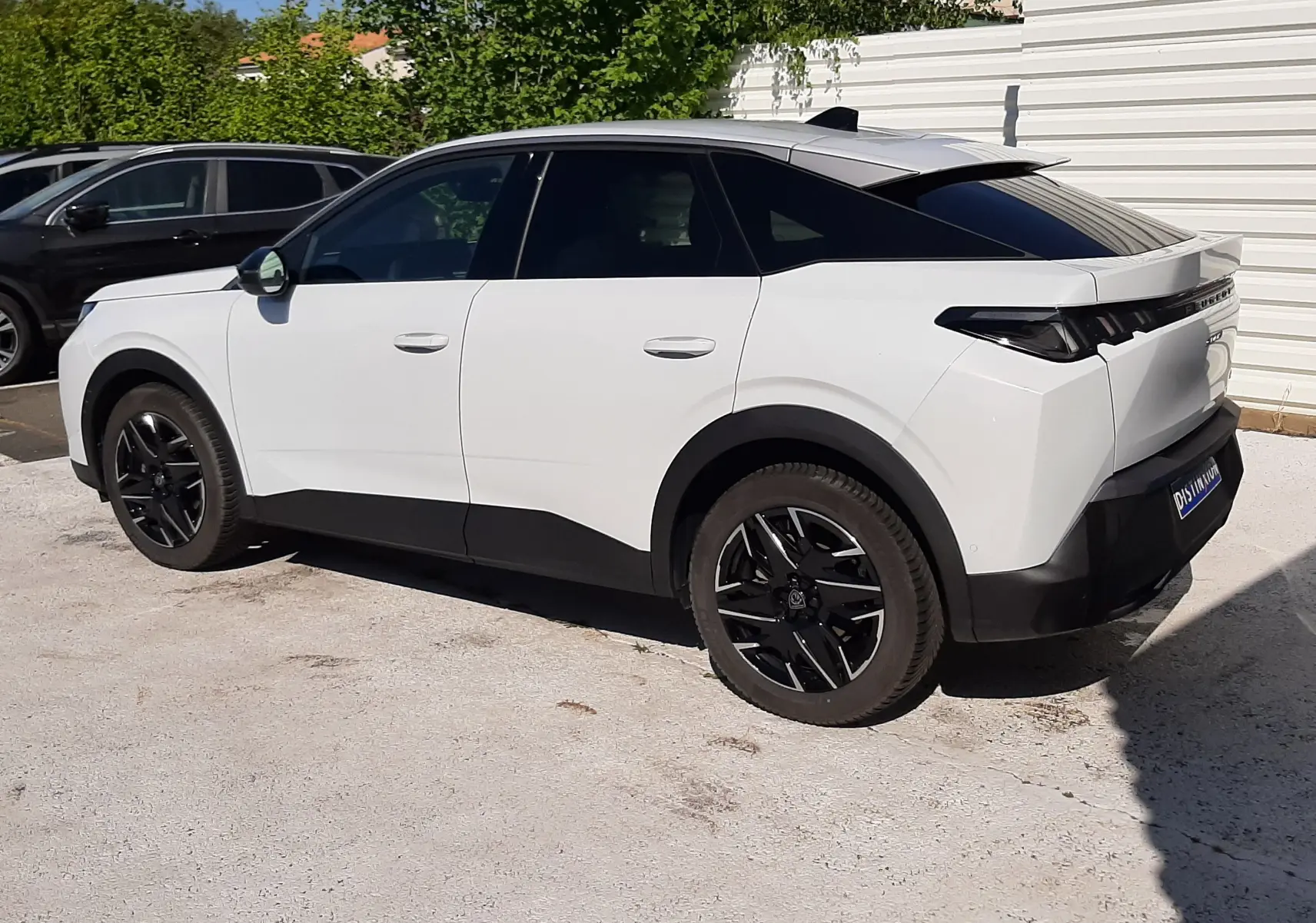 Peugeot 3008 hybride blanc Okenite vu de côté gauche arrière, avec toit noir et jantes noires distinctives.