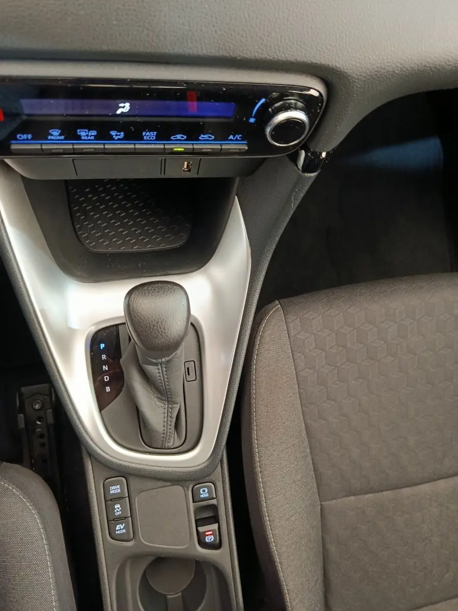 Vue intérieure centrée sur la console centrale et levier de vitesse automatique de la Toyota Yaris hybride 2022, sièges gris.