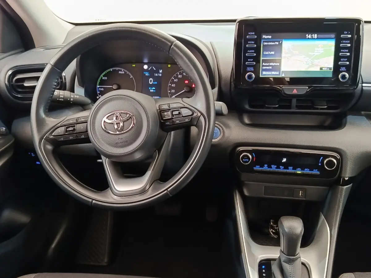 Vue intérieure centrée sur le volant cuir multifonctions et l’écran tactile du tableau de bord de la Toyota Yaris hybride.