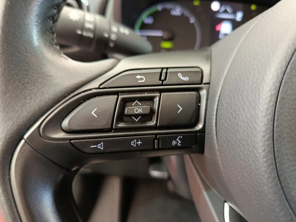 Gros plan sur les commandes multifonctions du volant cuir noir d'une Toyota Yaris hybride 2022, boutons de navigation et appel.