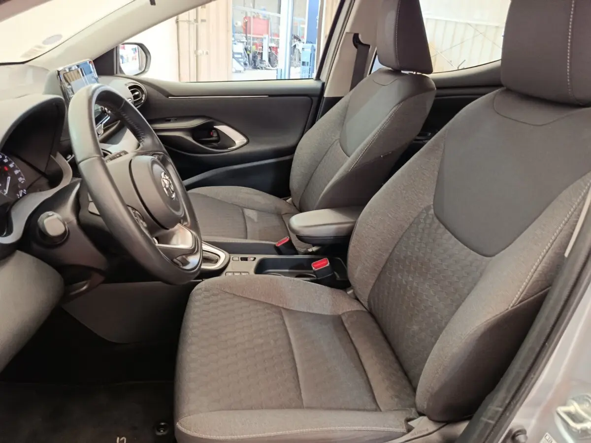 Intérieur avant gris clair de la Toyota Yaris Hybride 2022, vue côté conducteur avec volant cuir multifonctions.