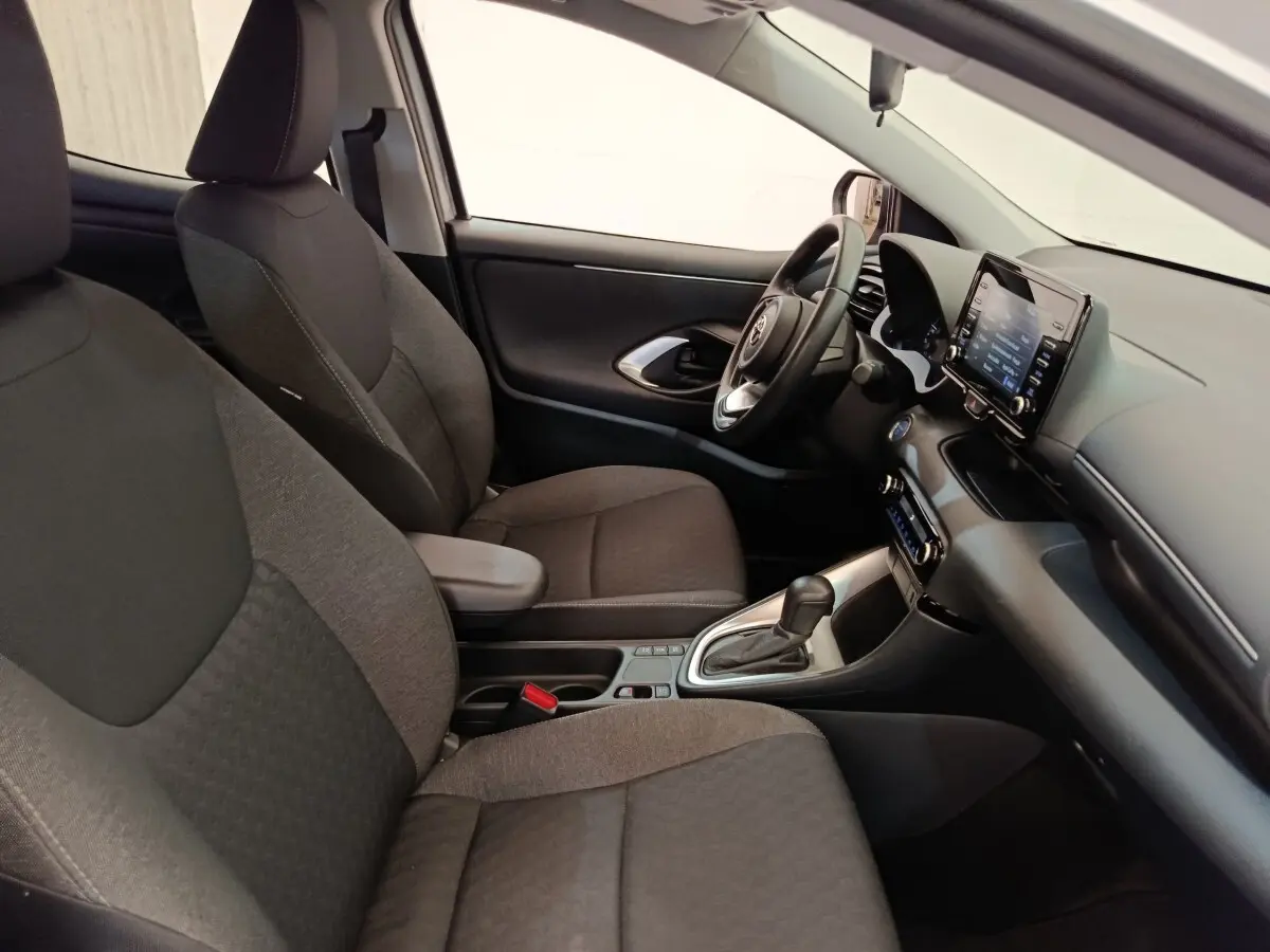 Intérieur avant droit de la Toyota Yaris hybride 2022, sièges tissu gris, volant cuir multifonctions et écran tactile central.