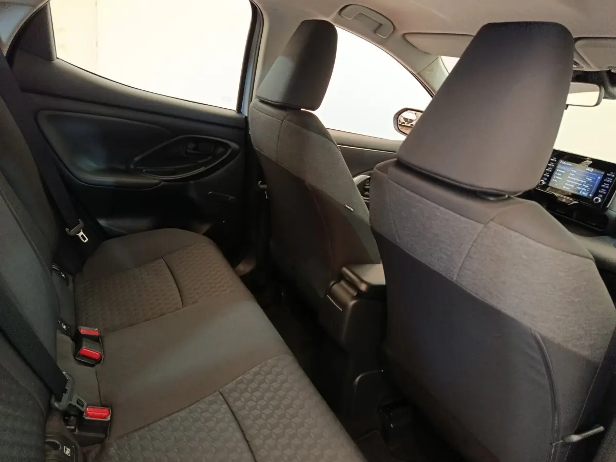 Vue intérieure arrière côté gauche de la Toyota Yaris hybride 2022, sièges tissu gris foncé avec motifs géométriques.