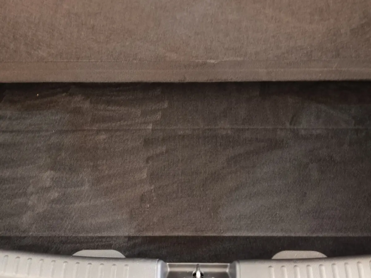 Vue plongeante sur le coffre gris clair de la Toyota Yaris hybride 2022, montrant la moquette et la tablette arrière.