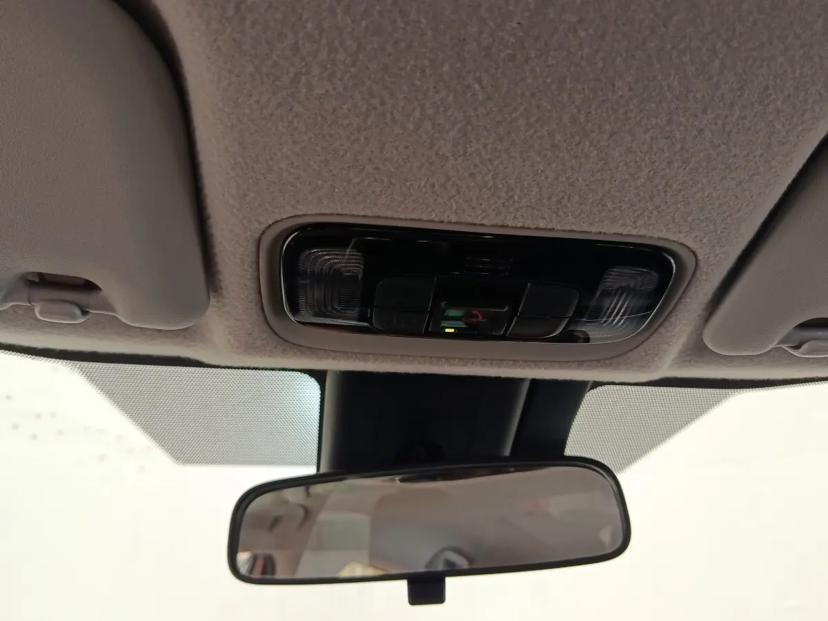 Plafonnier avec commandes intégrées et rétroviseur intérieur dans une Toyota Yaris hybride gris clair, vue de l'habitacle.