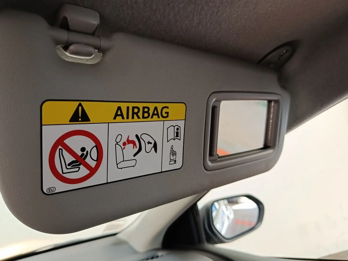 Détail du pare-soleil côté conducteur gris clair avec miroir et avertissement airbag dans une Toyota Yaris hybride 2022.