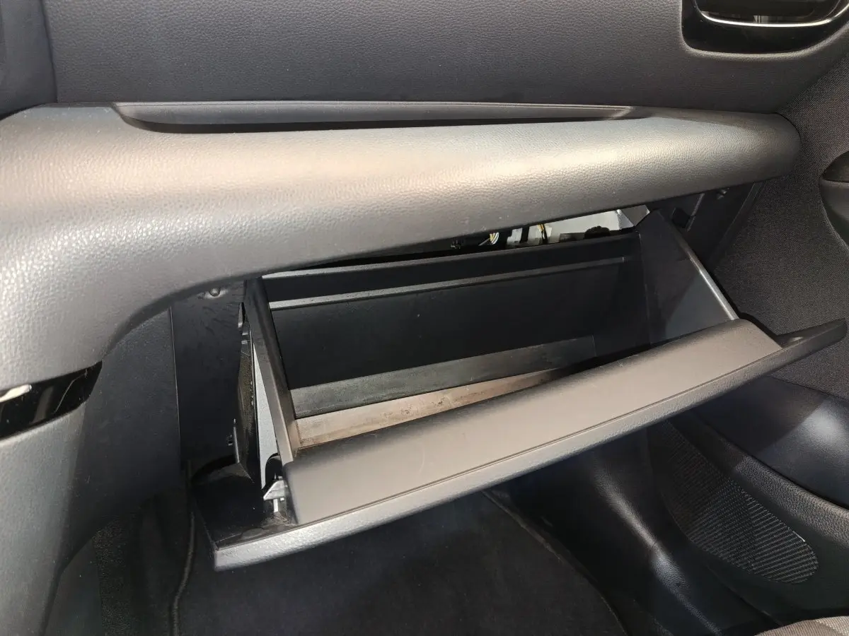 Gant de rangement ouvert côté passager dans l'habitacle gris foncé de la Toyota Yaris hybride 2022.