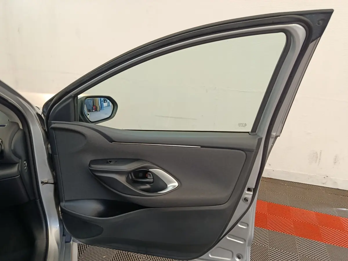 Vue intérieure de la porte avant gauche gris clair de la Toyota Yaris hybride 2022 avec poignée noire et garniture tissu.