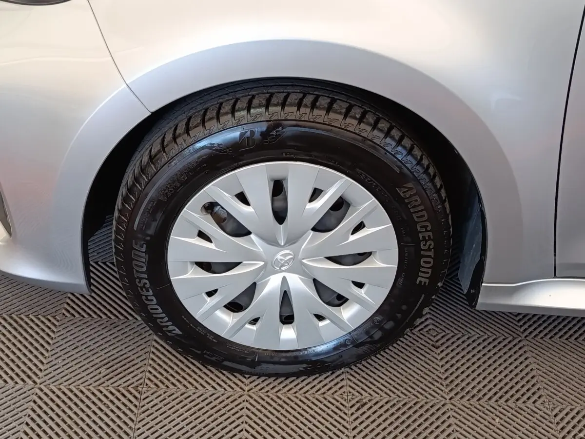 Gros plan sur la roue avant droite grise claire d'une Toyota Yaris hybride avec enjoliveur et pneu Bridgestone.