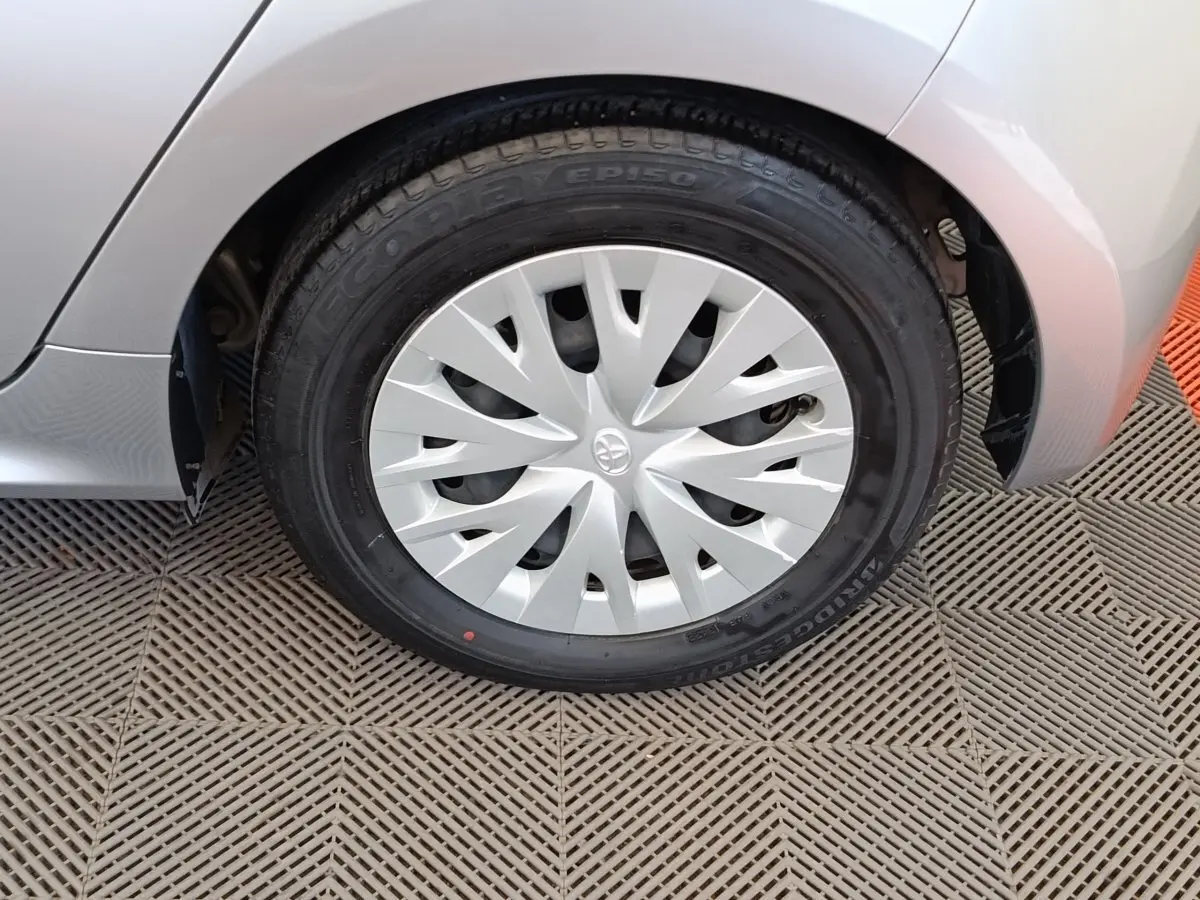 Gros plan sur la roue avant droite grise clair de la Toyota Yaris hybride avec enjoliveur à motifs dynamiques.
