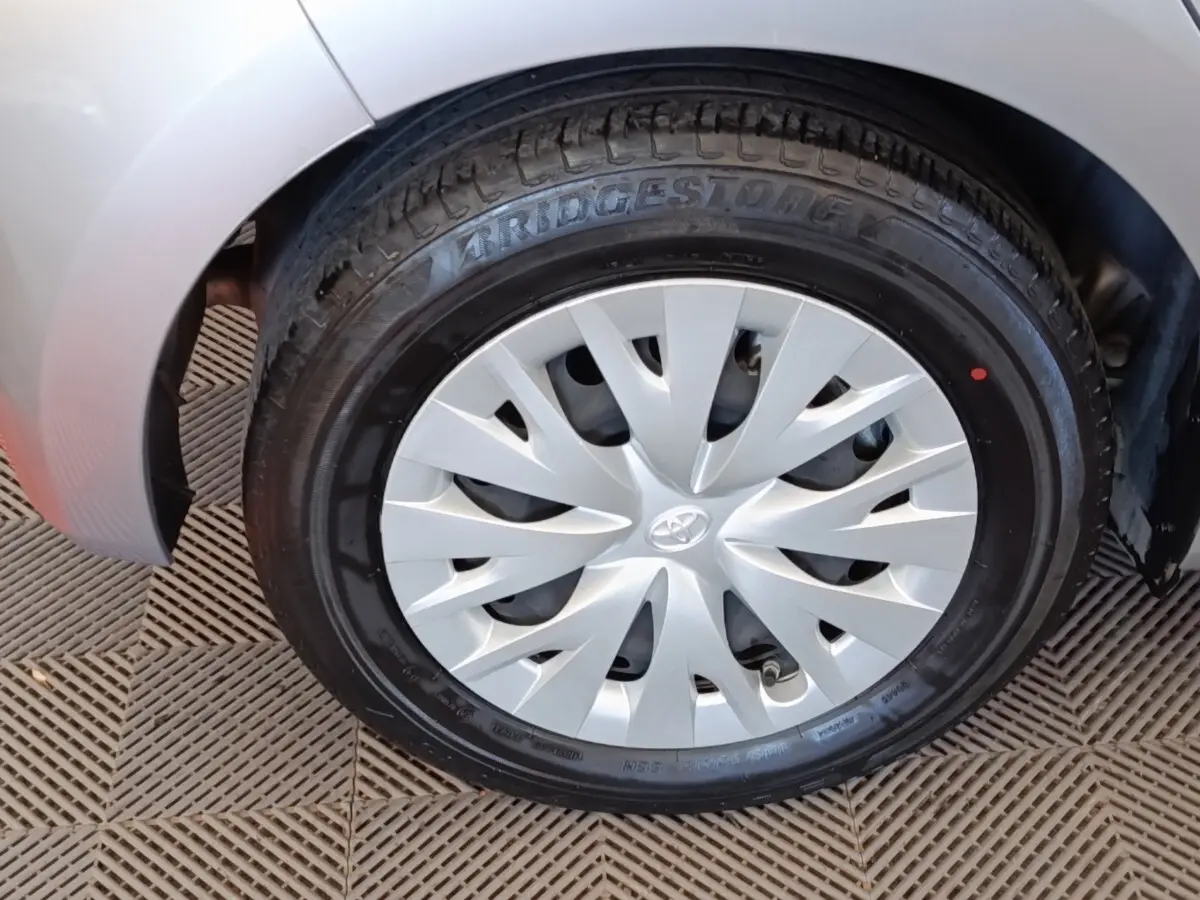 Gros plan sur la roue avant droite d'une Toyota Yaris hybride gris clair, avec jante en alliage et pneu Bridgestone.