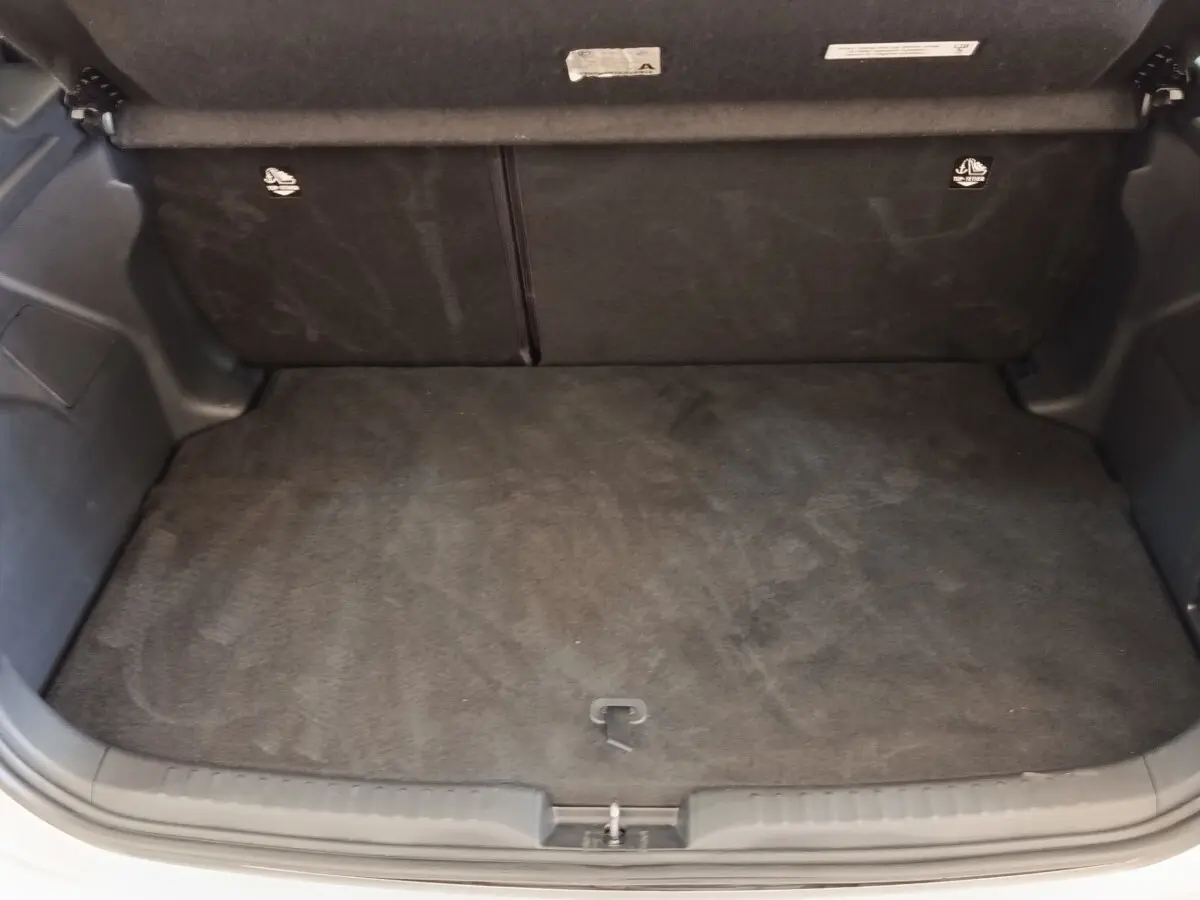 Coffre ouvert de la Toyota Yaris hybride gris clair 2022, montrant l'espace de chargement vide et la banquette arrière rabattable.