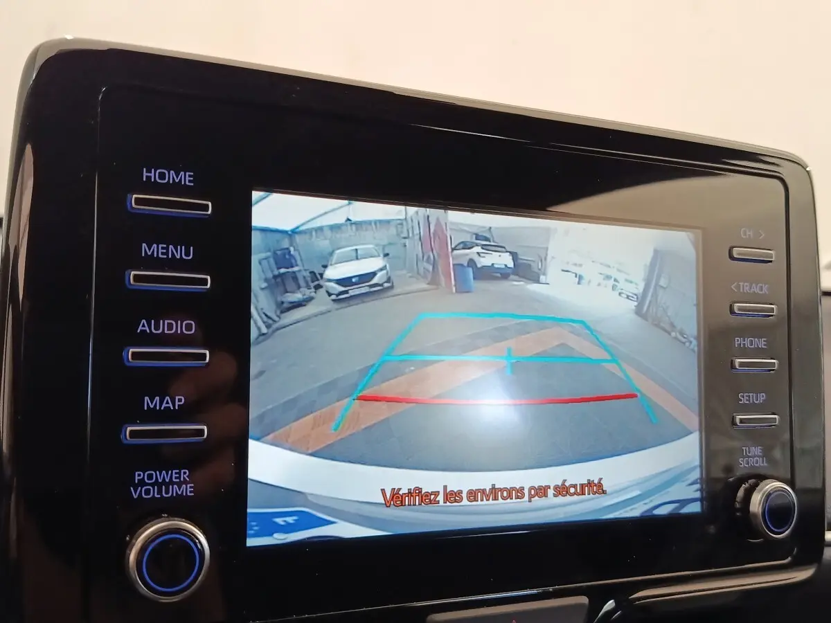 Vue arrière sur l'écran tactile de la Toyota Yaris hybride gris clair, affichant la caméra de recul avec guidage coloré.
