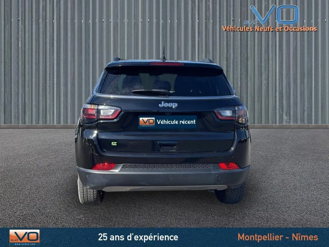 Vue arrière d'un Jeep Compass noir 2023 avec feux LED et logo e-Hybrid sur un sol goudronné.