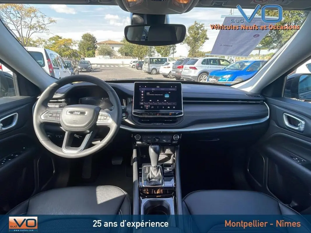 Vue intérieure avant du Jeep Compass noir 2023 avec tableau de bord moderne et écran tactile central.