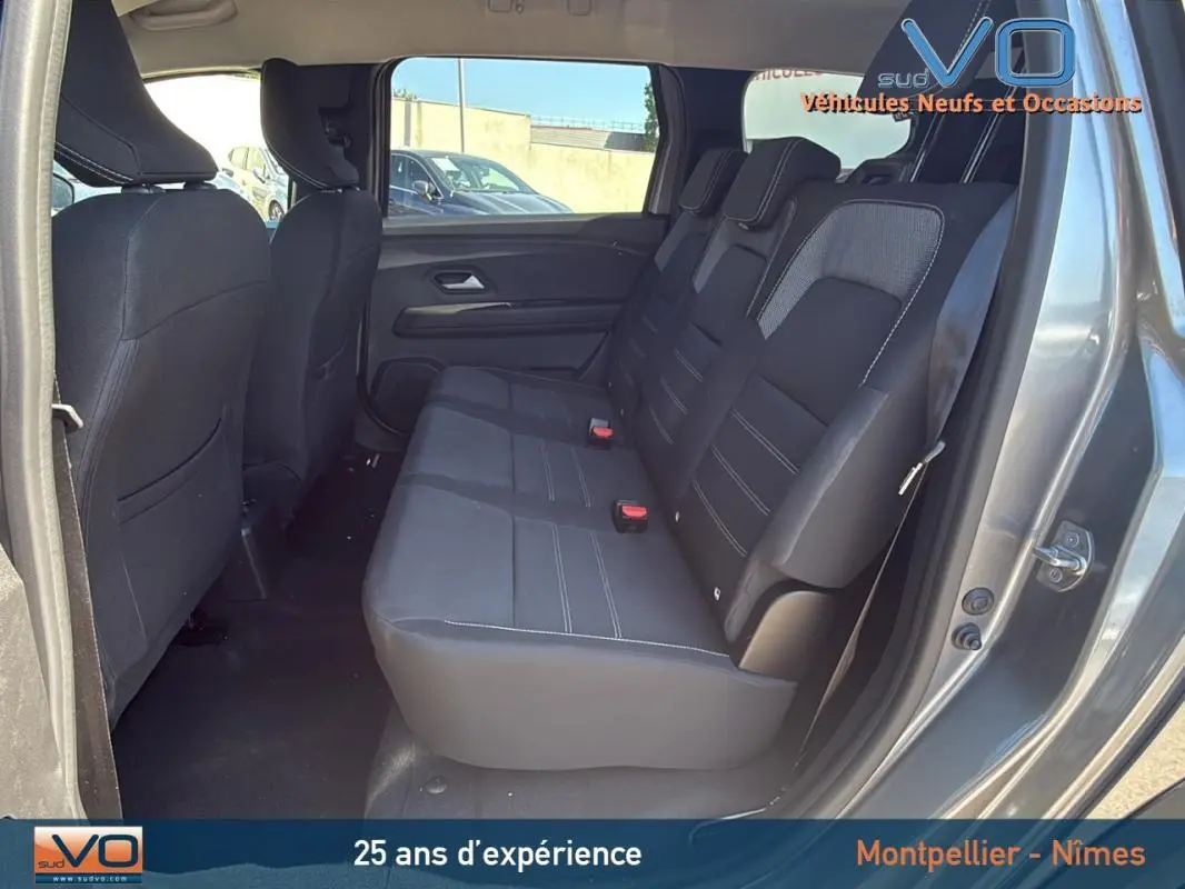 Vue latérale droite de l'intérieur arrière du Dacia Jogger gris 2025, montrant les sièges 3 places et les portes ouvertes.