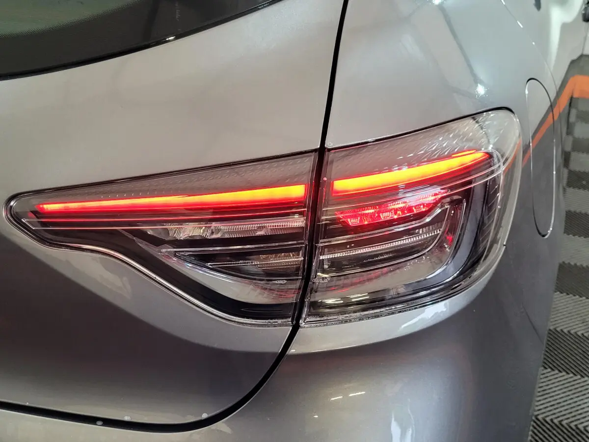 Gros plan sur le feu arrière droit rouge allumé d'une Renault Clio gris foncé Evolution Blue dCi 100 2025.