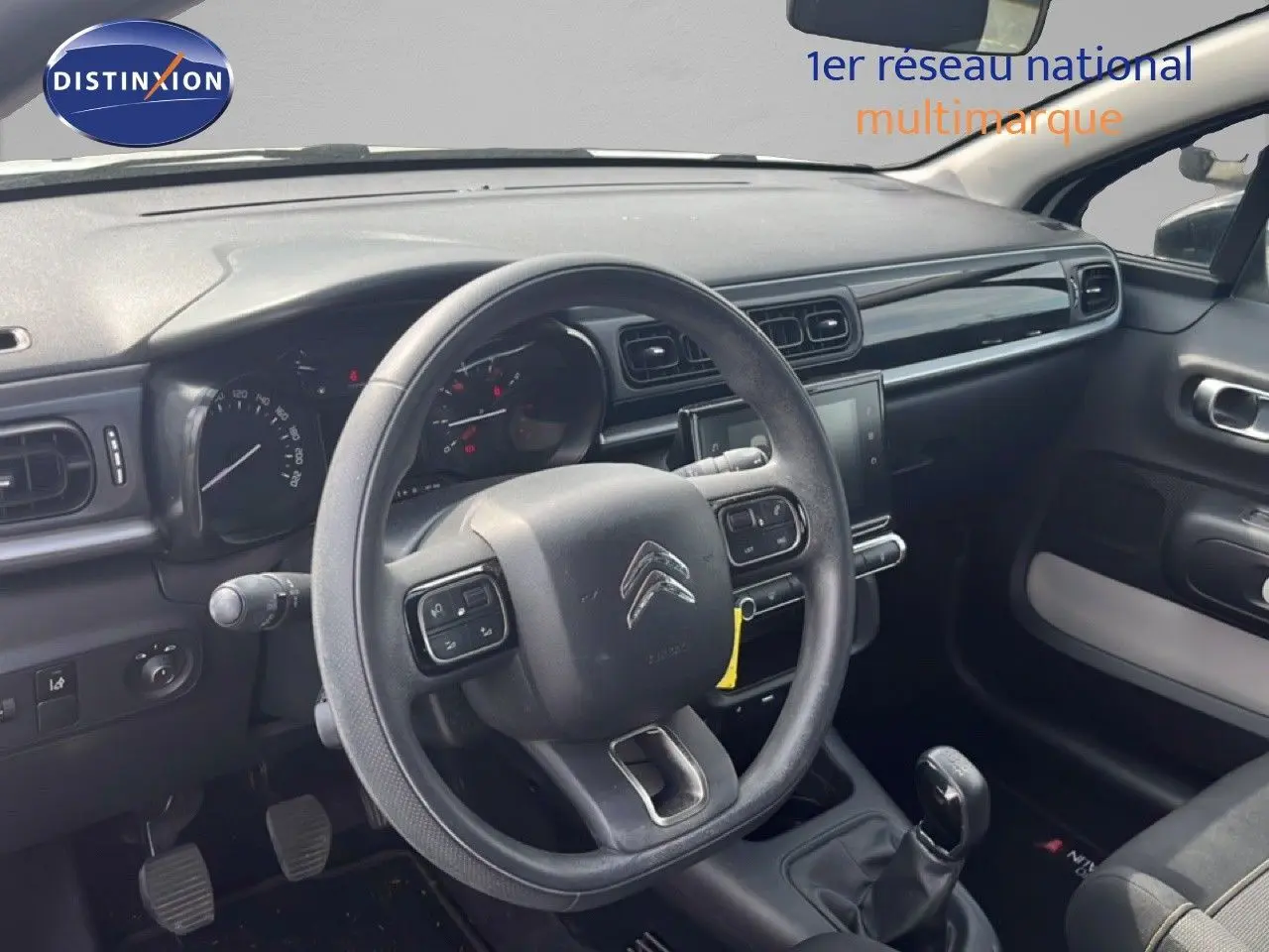 Vue intérieure côté conducteur du tableau de bord et volant de la Citroën C3 2018 en tissu noir avec boîte manuelle.