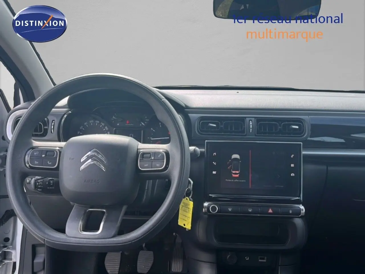 Vue intérieure frontale du tableau de bord et du volant de la Citroën C3 blanche de 2018 avec écran tactile central.