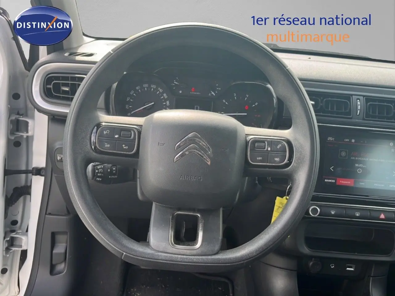 Vue intérieure centrée sur le volant noir d'une Citroën C3 blanche de 2018 avec tableau de bord et écran tactile visibles.