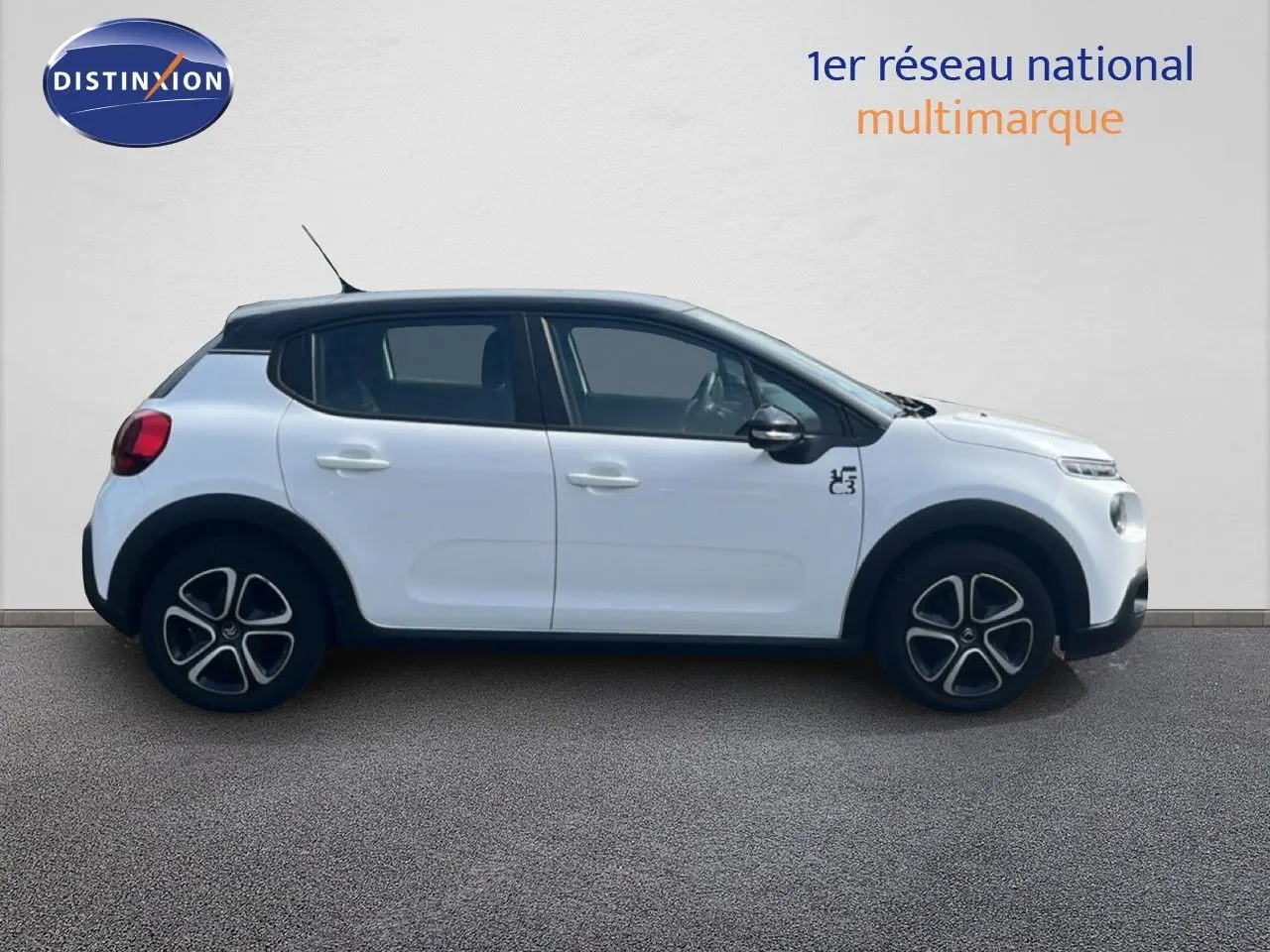 Profil droit d'une Citroën C3 blanche 2018 avec toit noir et jantes distinctives, sur fond neutre intérieur.