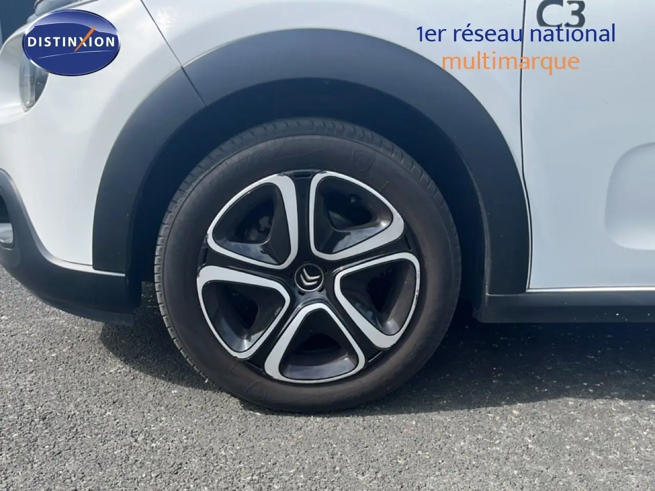 Gros plan sur la roue avant gauche d'une Citroën C3 blanche de 2018 avec jante noire et argentée au design distinctif.