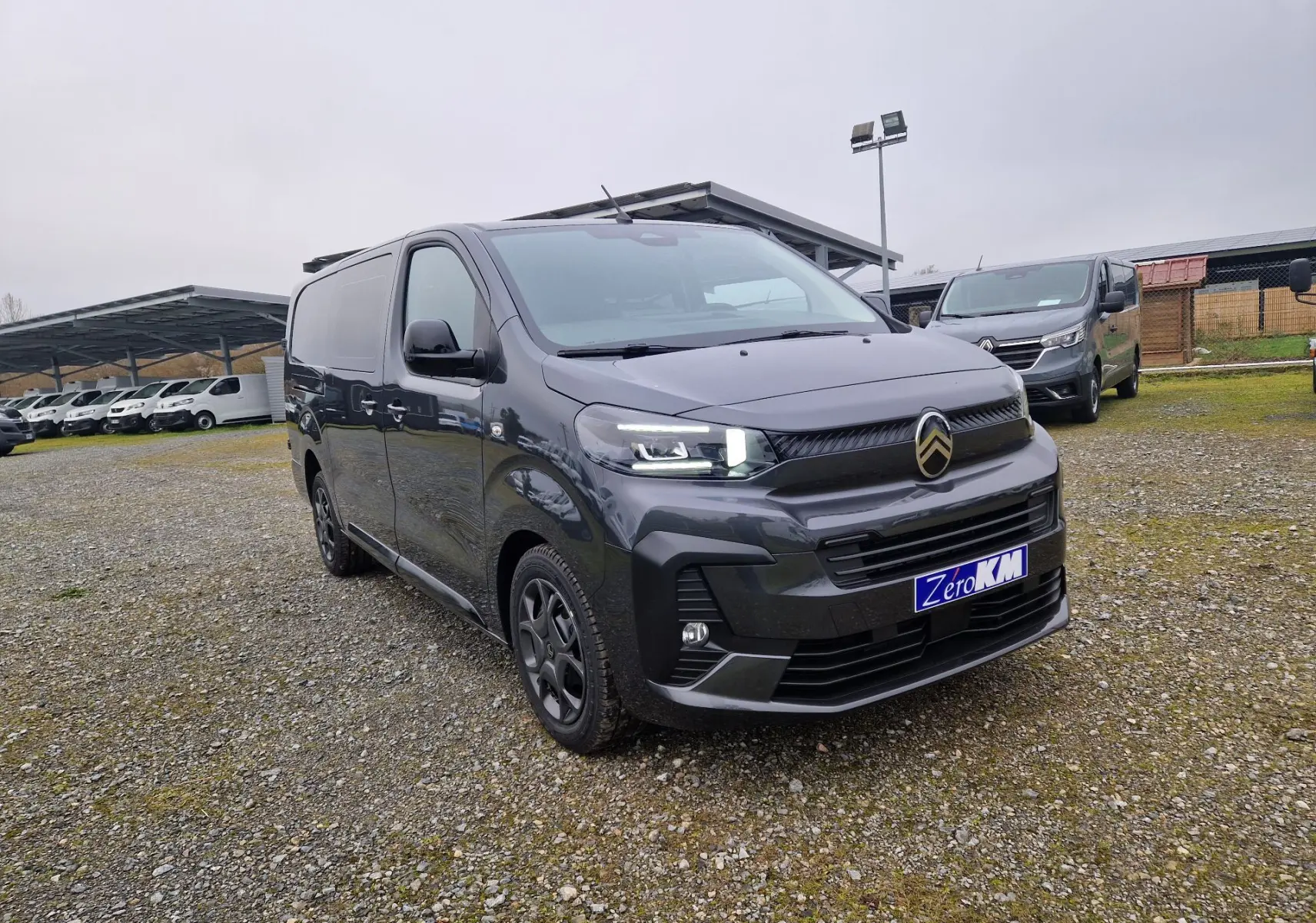 Citroën Jumpy Cabine Approfondie gris titane, vue 3/4 avant droit, avec phares LED allumés sur parking extérieur.