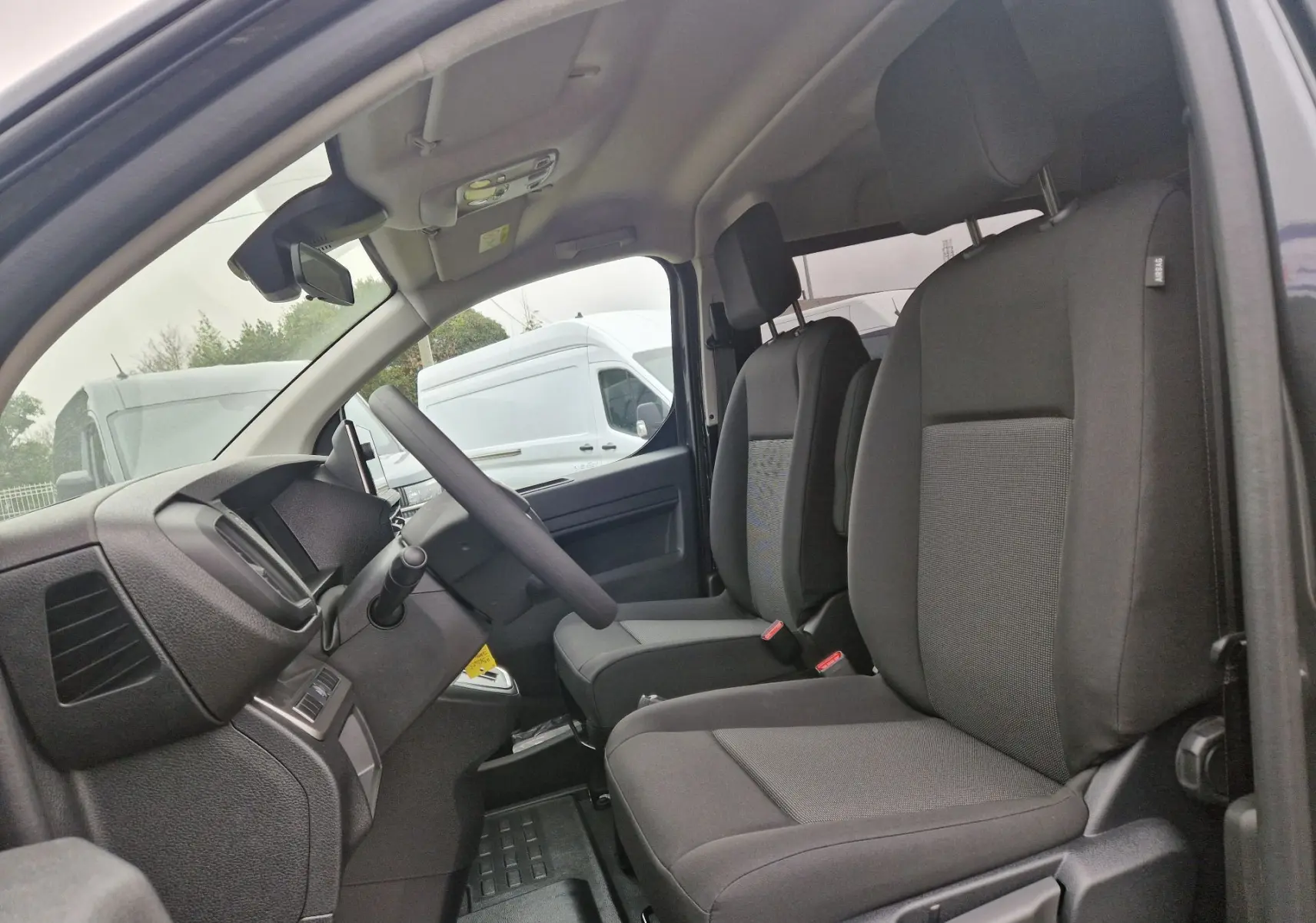 Vue intérieure côté gauche du poste de conduite du Citroën Jumpy Cabine Approfondie gris titane avec sièges noirs.