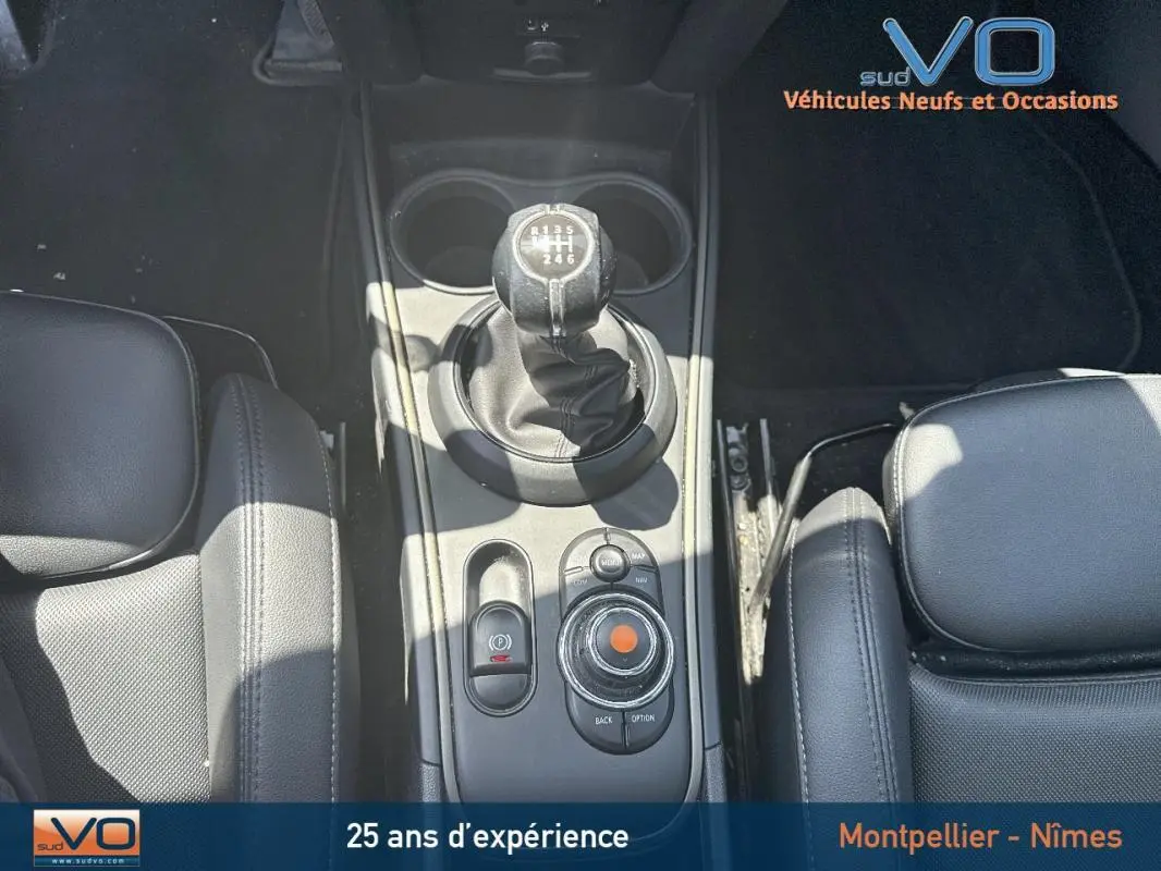 Vue plongeante sur la console centrale de la MINI Countryman gris clair, mettant en valeur le levier de vitesses manuel et l'accoudoir central cuir noir.