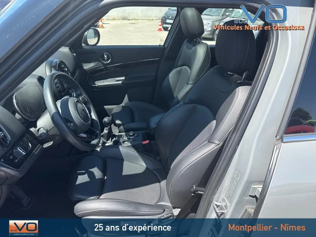Intérieur côté conducteur d'une MINI Countryman gris clair 2021 avec sièges cuir noirs et volant sport.