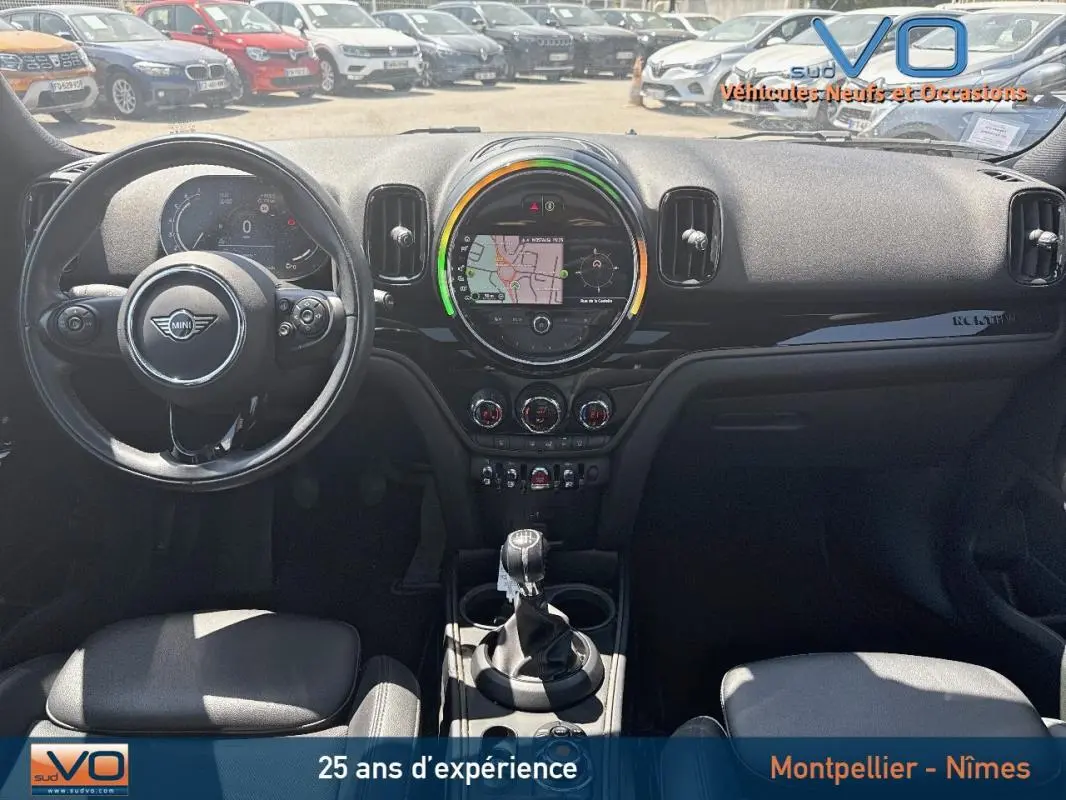 Vue intérieure avant du tableau de bord d'une MINI Countryman gris clair avec écran tactile central et volant sport.
