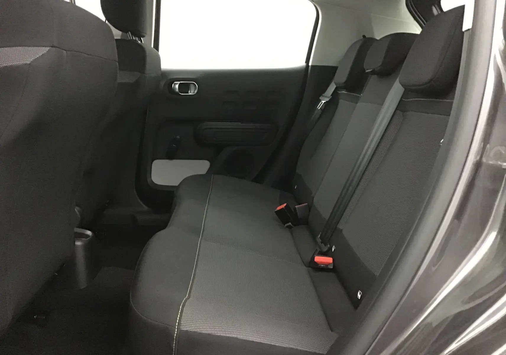 Vue intérieure côté droit des sièges arrière noirs de la Citroën C3 gris platinium 2022, avec ceintures de sécurité visibles.