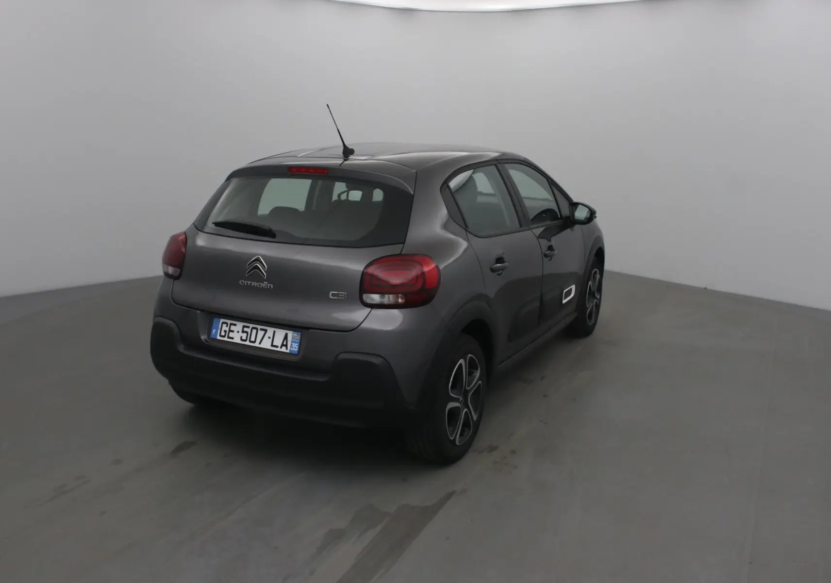Citroën C3 gris platinium vue 3/4 arrière droit, avec feux arrière arrondis et jantes spécifiques.