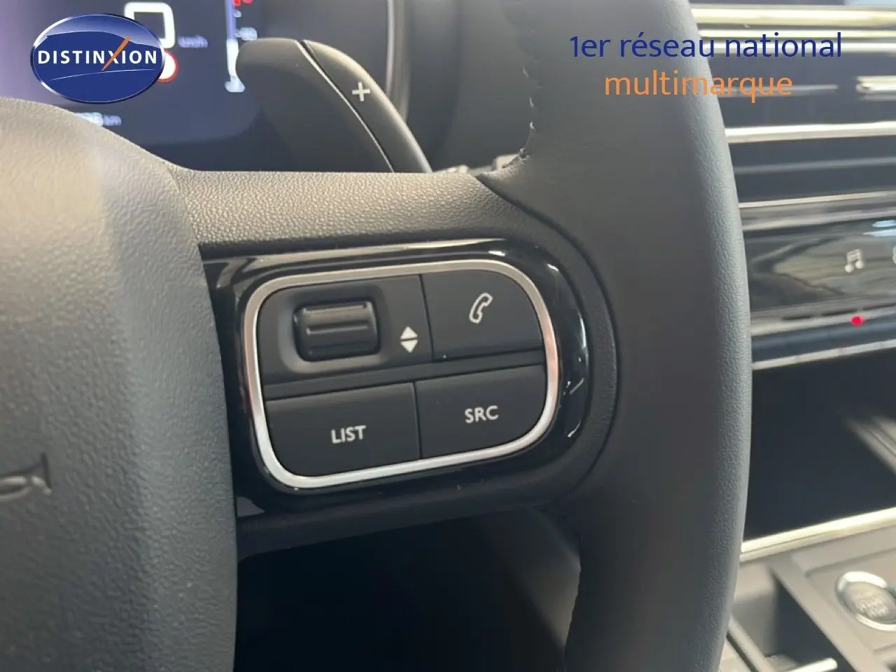 Gros plan sur les commandes au volant noir du Citroën C5 Aircross 1.2 Hybride 2025, intérieur noir métal.