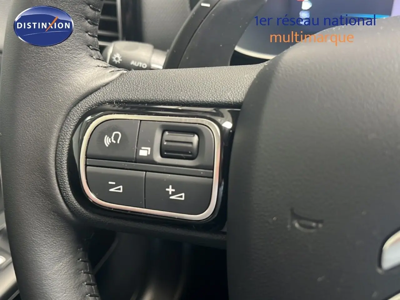 Gros plan sur les commandes gauche du volant noir du Citroën C5 Aircross hybride 2025, avec boutons de réglage audio.