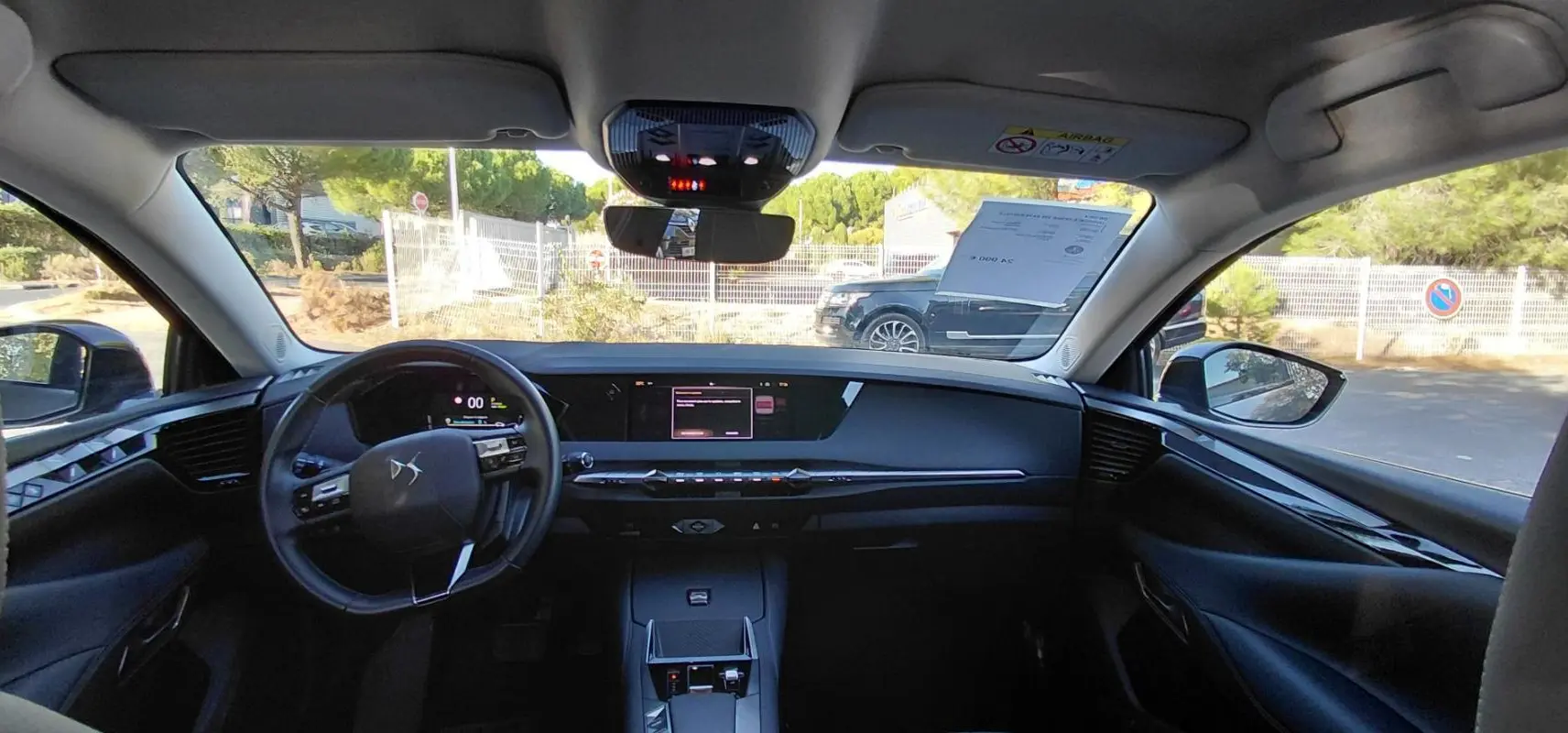 Vue intérieure avant du DS4 Hybride E-Tense 225 gris, mettant en valeur le tableau de bord digital et le volant compact.