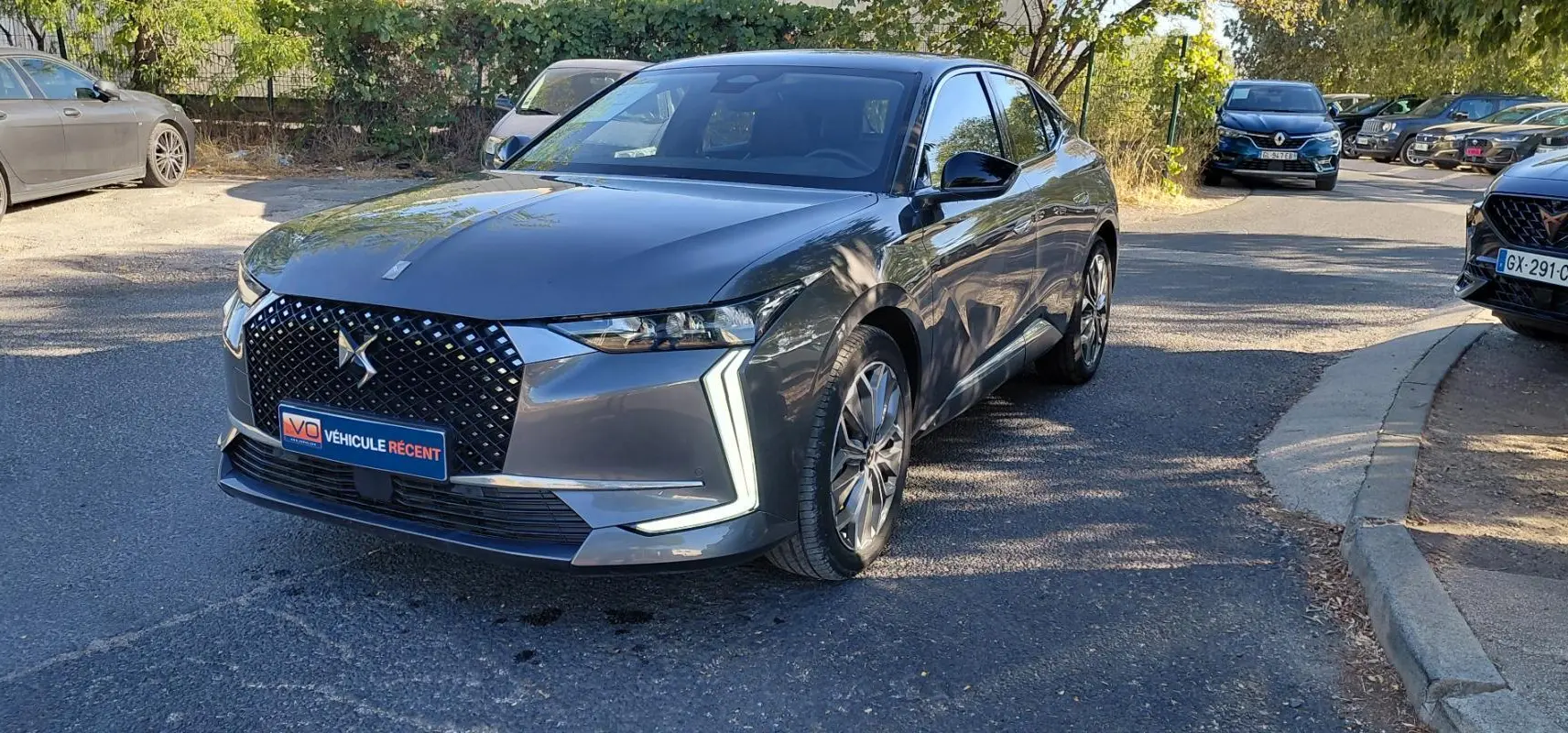 DS4 Hybride E-Tense 225 gris 2024 vue 3/4 avant droit, calandre distinctive avec logo DS et feux LED en forme de flèche.