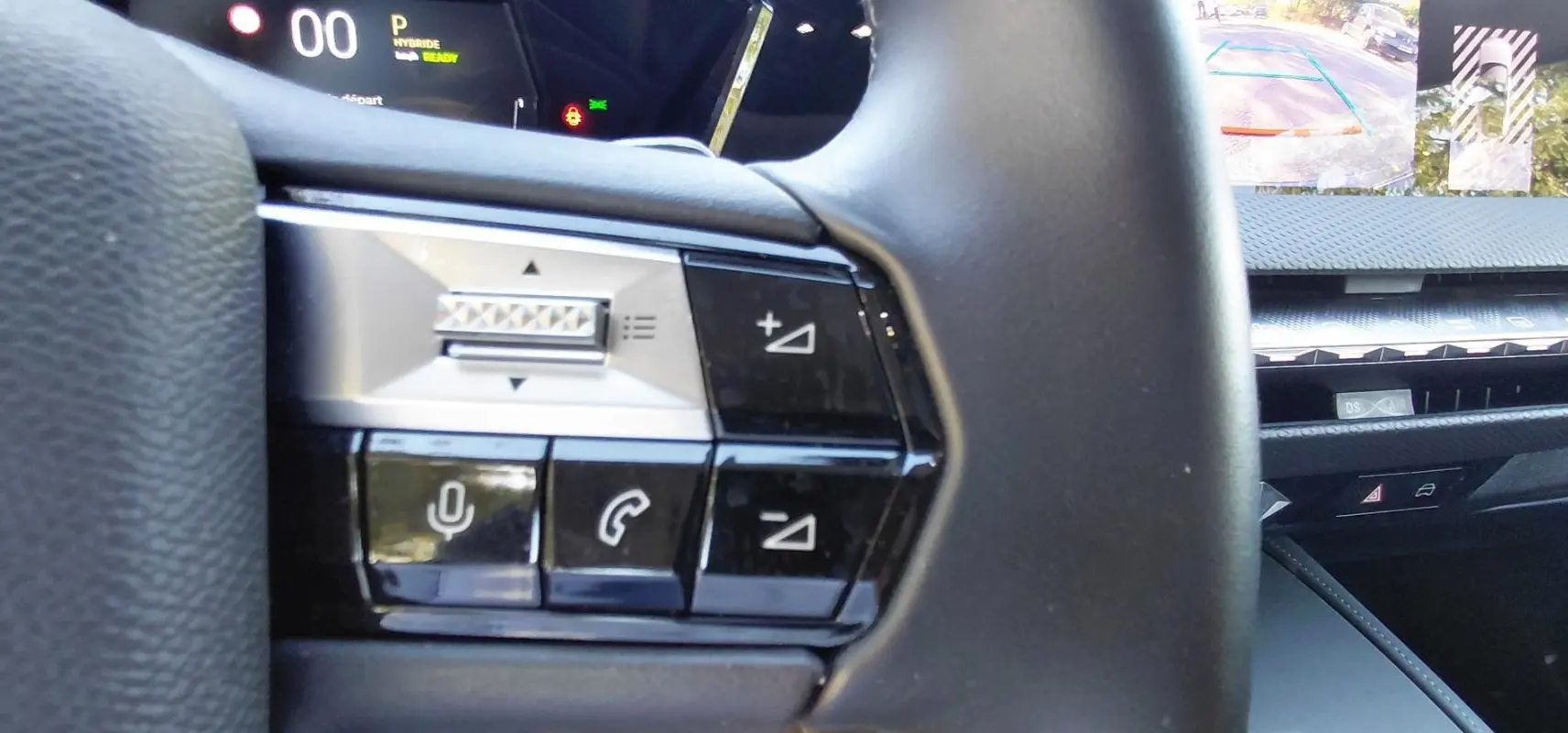 Gros plan sur les commandes au volant du DS4 gris 2024 Hybride E-Tense, avec écran numérique et caméra de recul visible.