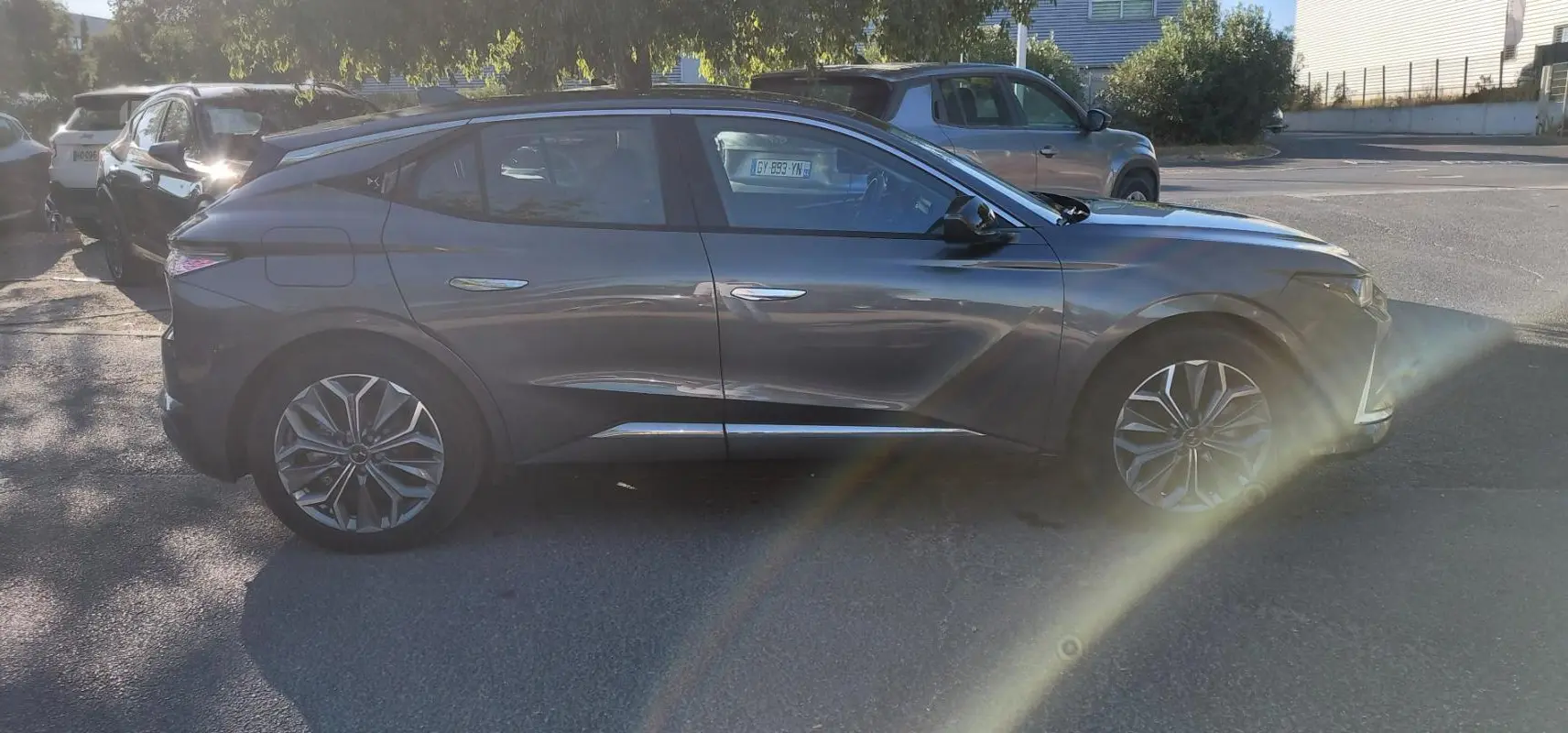 Vue de profil côté gauche d'une DS4 hybride gris métallisé 2024, soulignant ses lignes dynamiques et ses jantes distinctives.