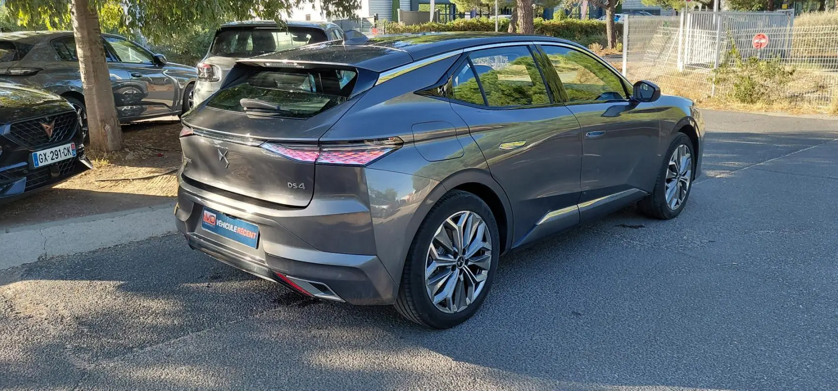 Vue 3/4 arrière droite d'une DS4 hybride gris métallisé 2024 avec feux arrière distinctifs et jantes stylisées.