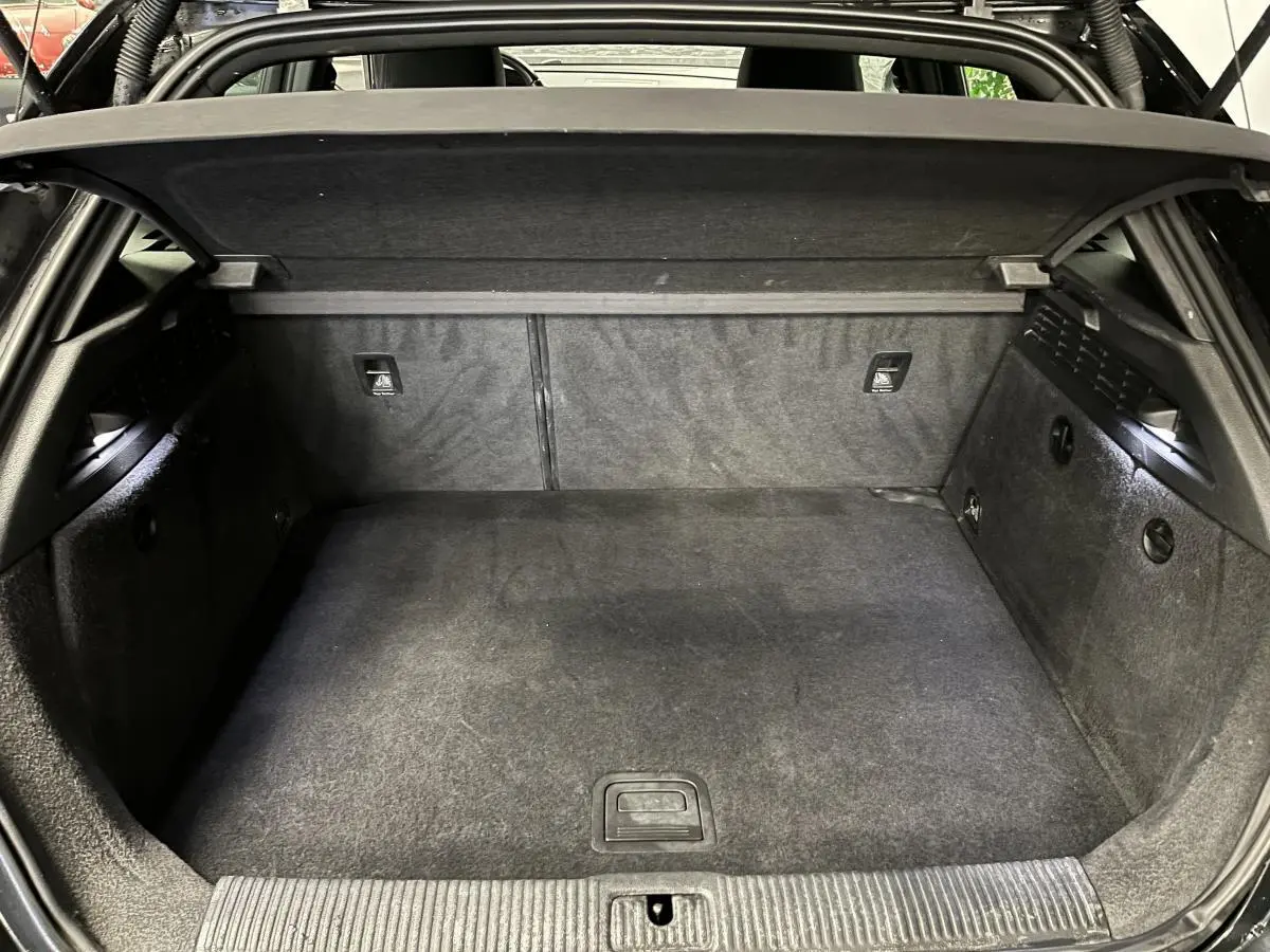 Coffre ouvert vu de face d'une Audi A3 1.4 TFSI e-tron S line noire avec intérieur de coffre en tissu gris foncé.